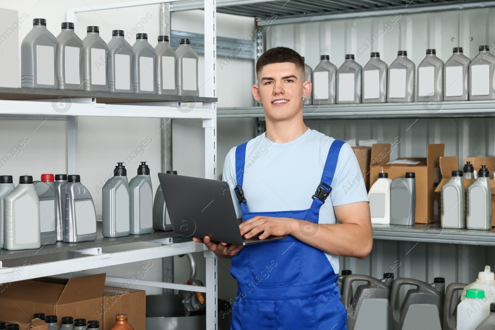 Photo of Smiling young man with laptop and different car products in auto store