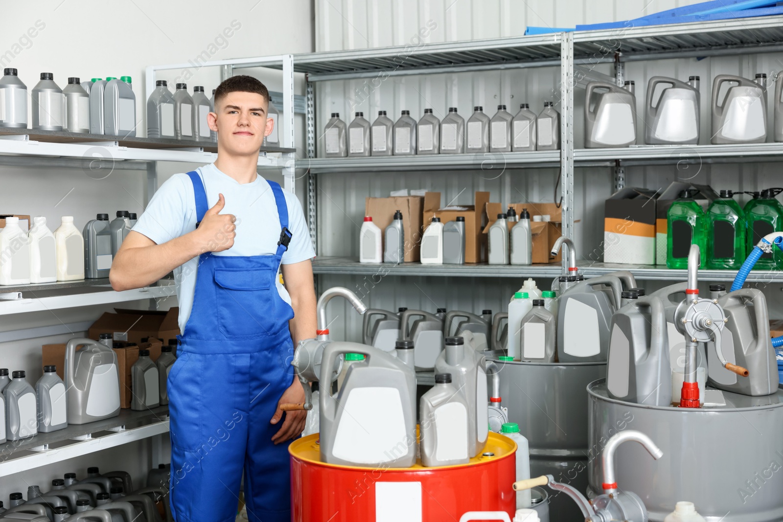 Photo of Young man showing thumbs up in auto store with different car products