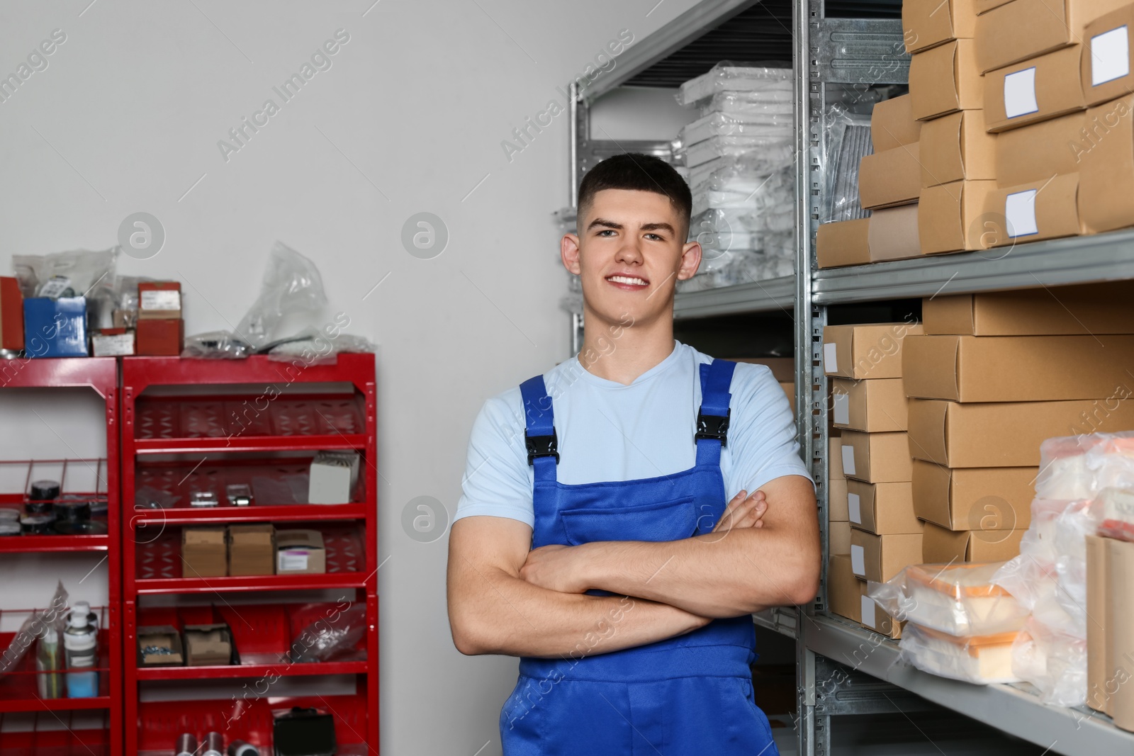 Photo of Smiling young man near many cardboard boxes in auto store