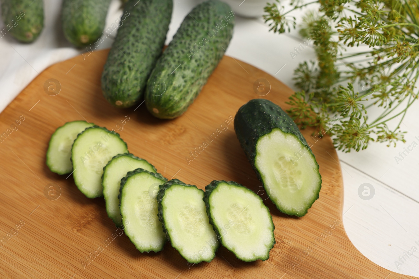 Photo of Fresh whole and cut cucumbers on white wooden table