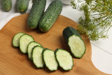 Photo of Fresh whole and cut cucumbers on white wooden table