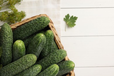 Fresh green cucumbers in box and spices on white wooden table, top view. Space for text