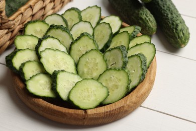 Photo of Fresh whole and cut cucumbers on white wooden table