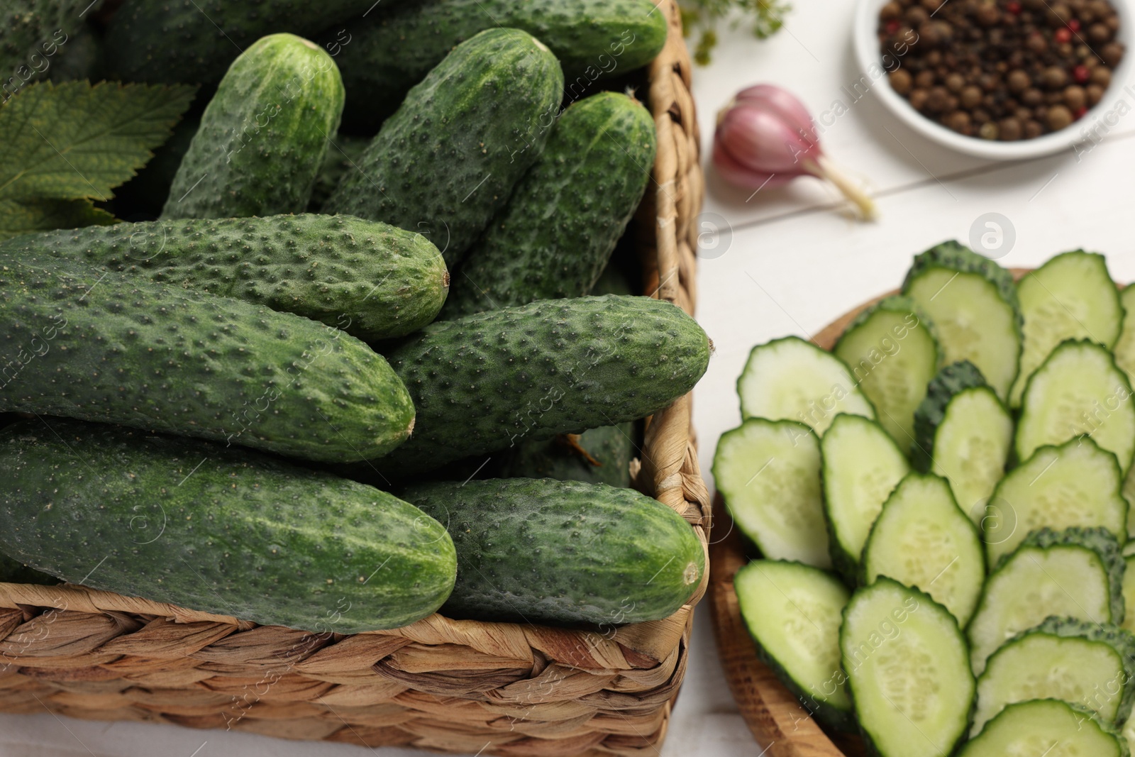 Photo of Fresh whole and cut cucumbers on white wooden table, closeup