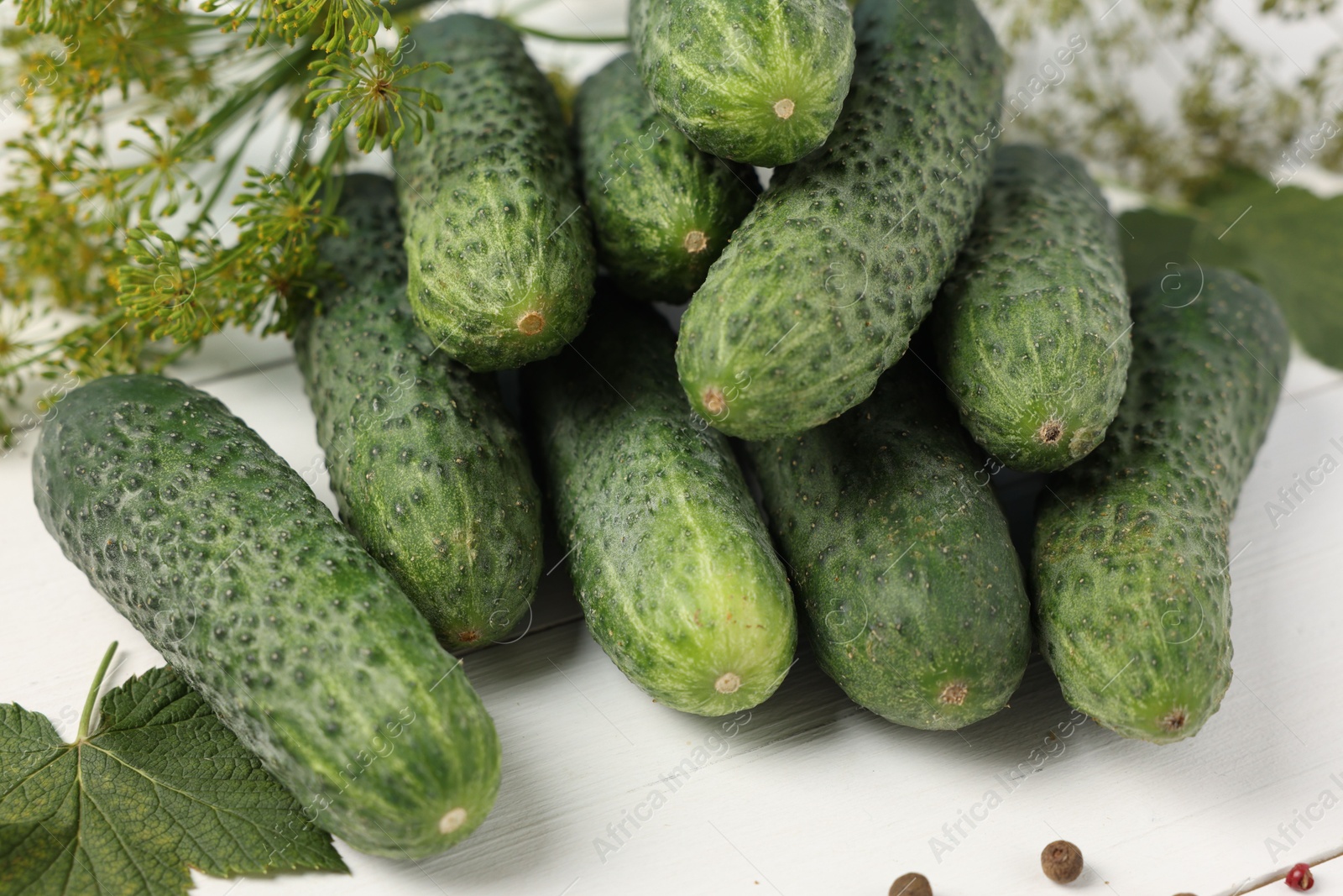 Photo of Fresh green cucumbers and spices on white wooden table, closeup