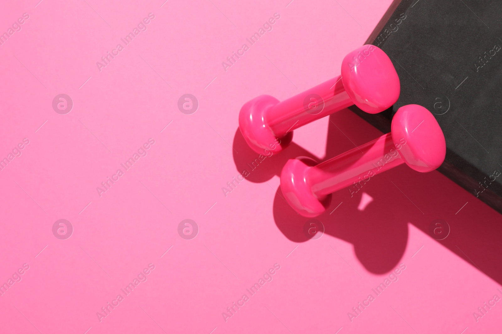 Photo of Dumbbells and yoga block on pink background, flat lay. Space for text