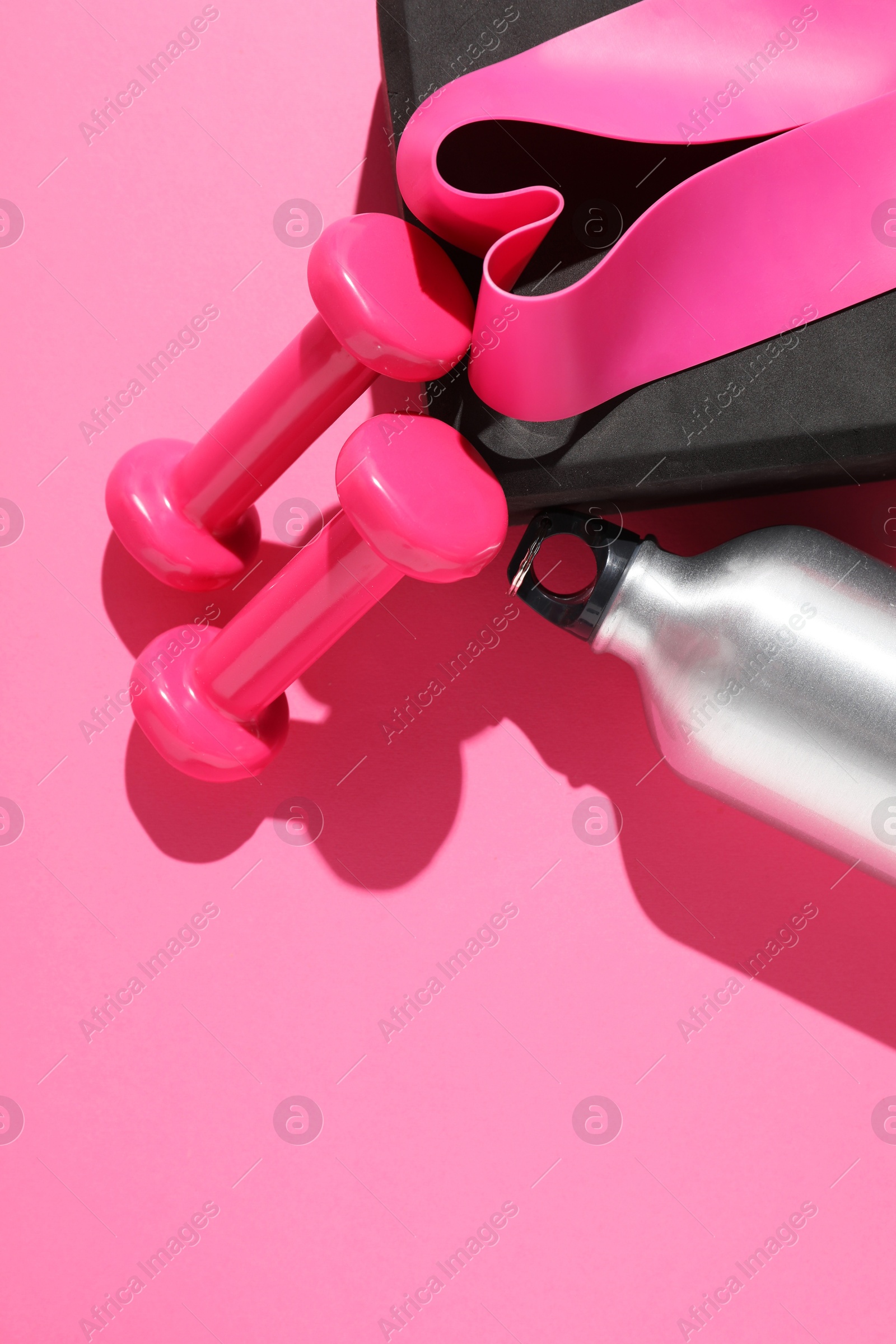 Photo of Dumbbells, fitness elastic band, water bottle and yoga block on pink background, flat lay. Space for text