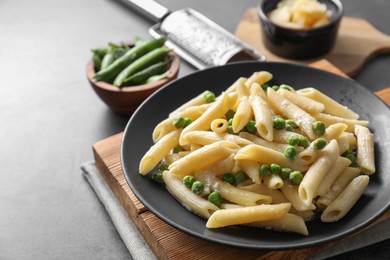 Photo of Delicious pasta with green peas, cheese and grater on grey table