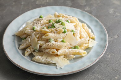 Photo of Delicious pasta with green peas, cheese and creamy sauce on grey table