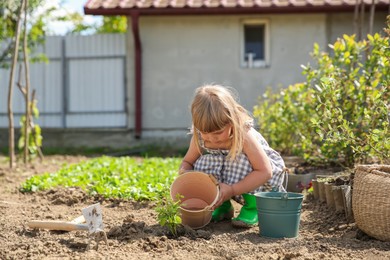 Photo of Cute little girl spending time in garden on spring day