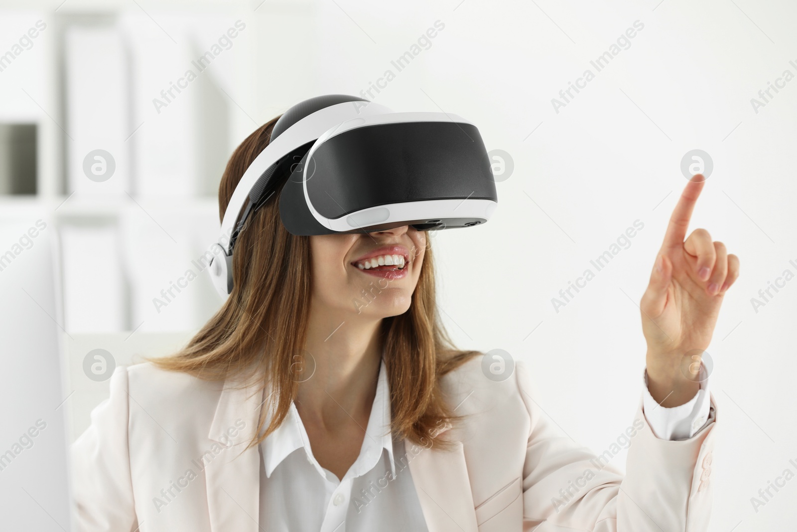 Photo of Smiling woman using virtual reality headset in office