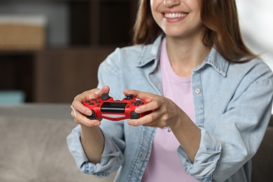 Photo of Smiling woman playing video game with controller at home, closeup