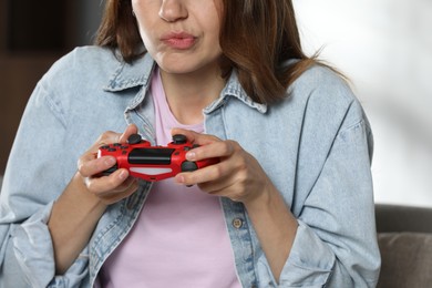 Photo of Woman playing video game with controller at home, closeup