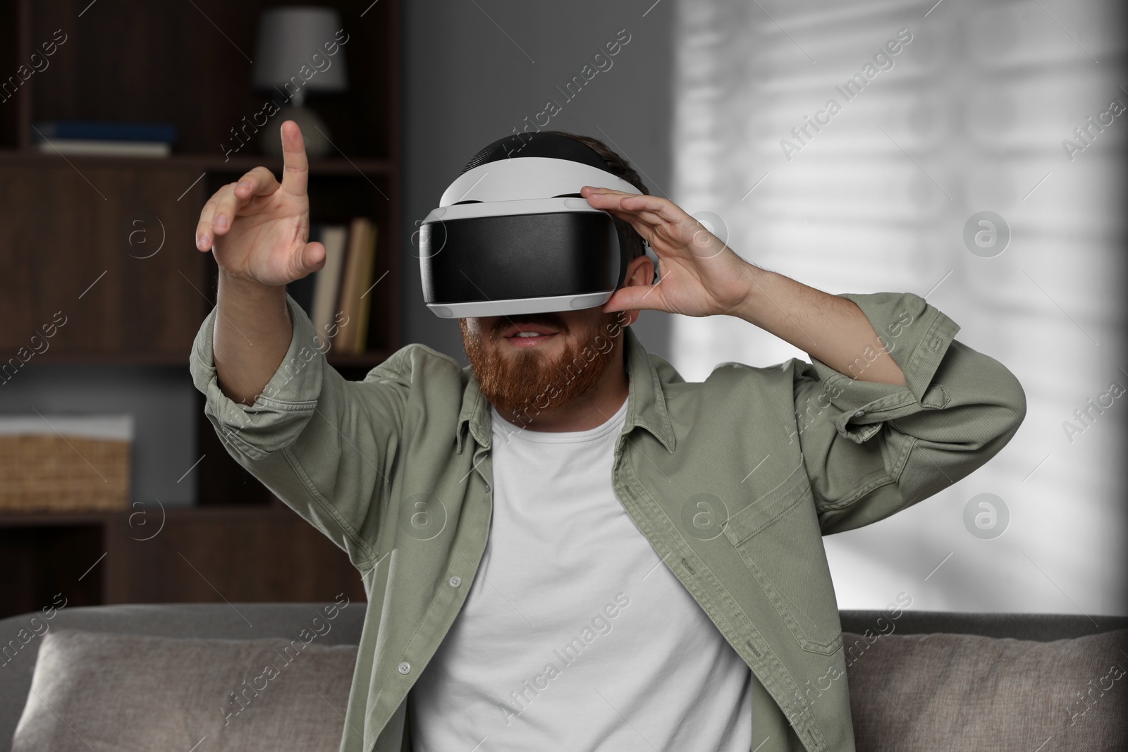 Photo of Man using virtual reality headset on sofa at home