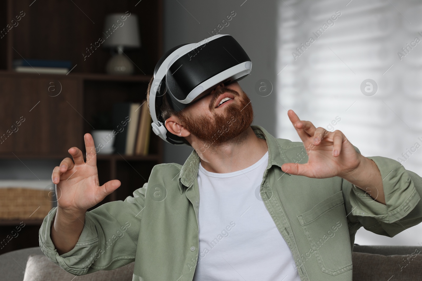 Photo of Man using virtual reality headset on sofa at home