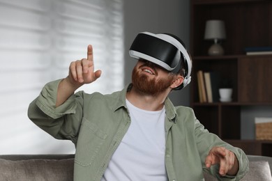 Photo of Man using virtual reality headset on sofa at home