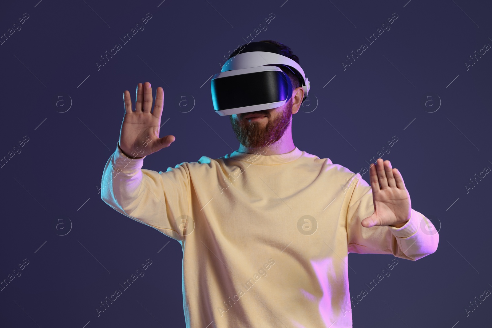 Photo of Man using virtual reality headset on dark purple background