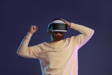 Photo of Man using virtual reality headset on dark purple background