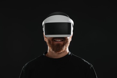 Photo of Smiling man using virtual reality headset on black background