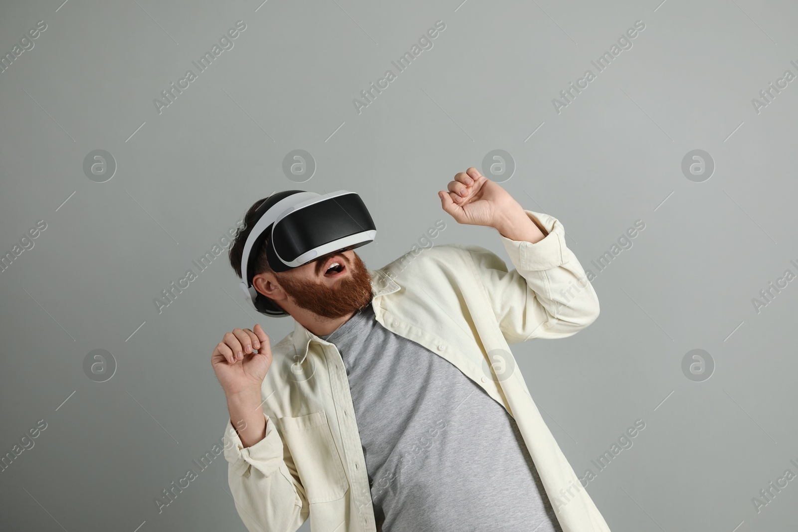 Photo of Emotional man using virtual reality headset on grey background