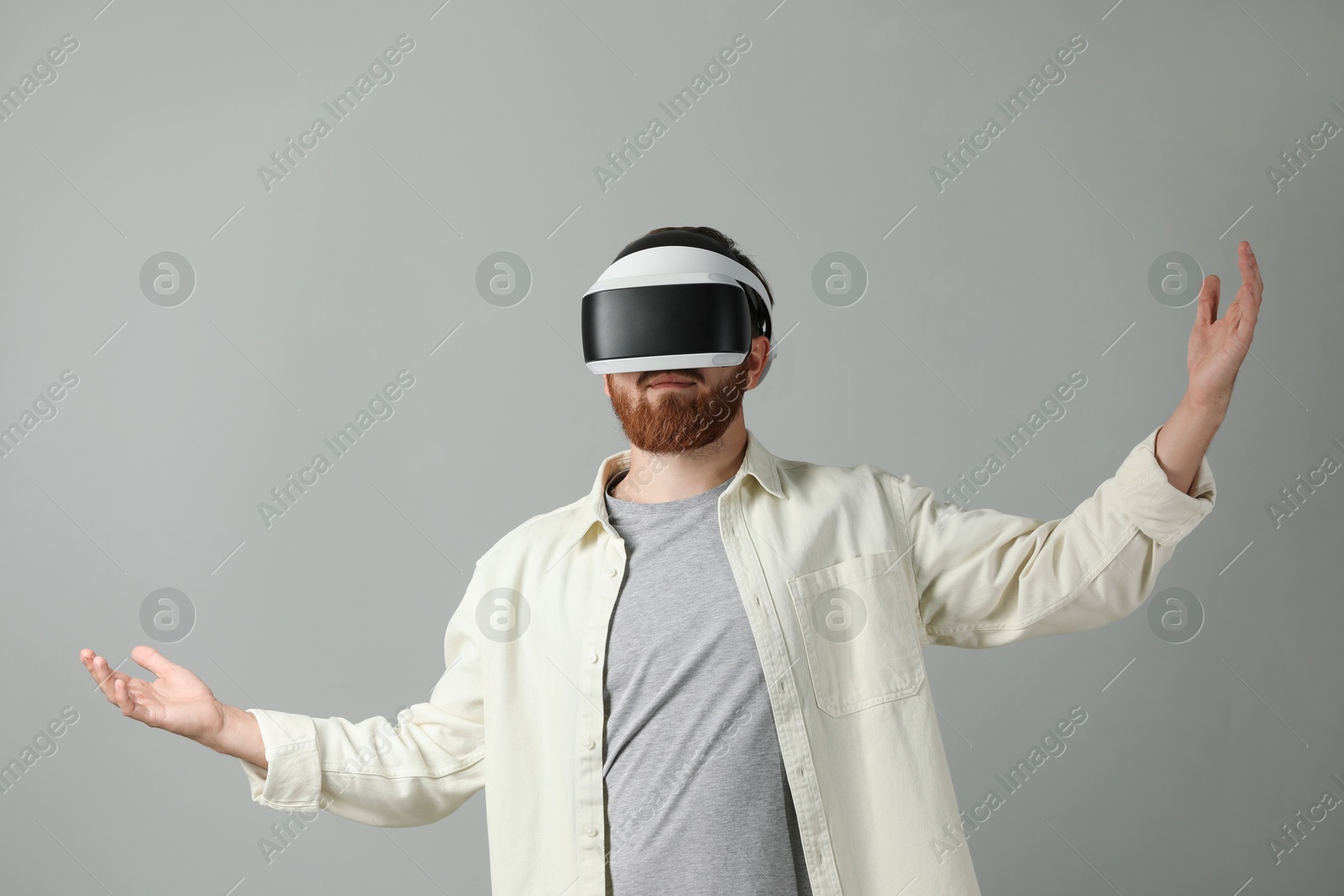 Photo of Man using virtual reality headset on grey background