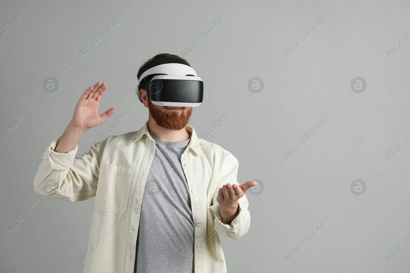 Photo of Man using virtual reality headset on grey background. Space for text