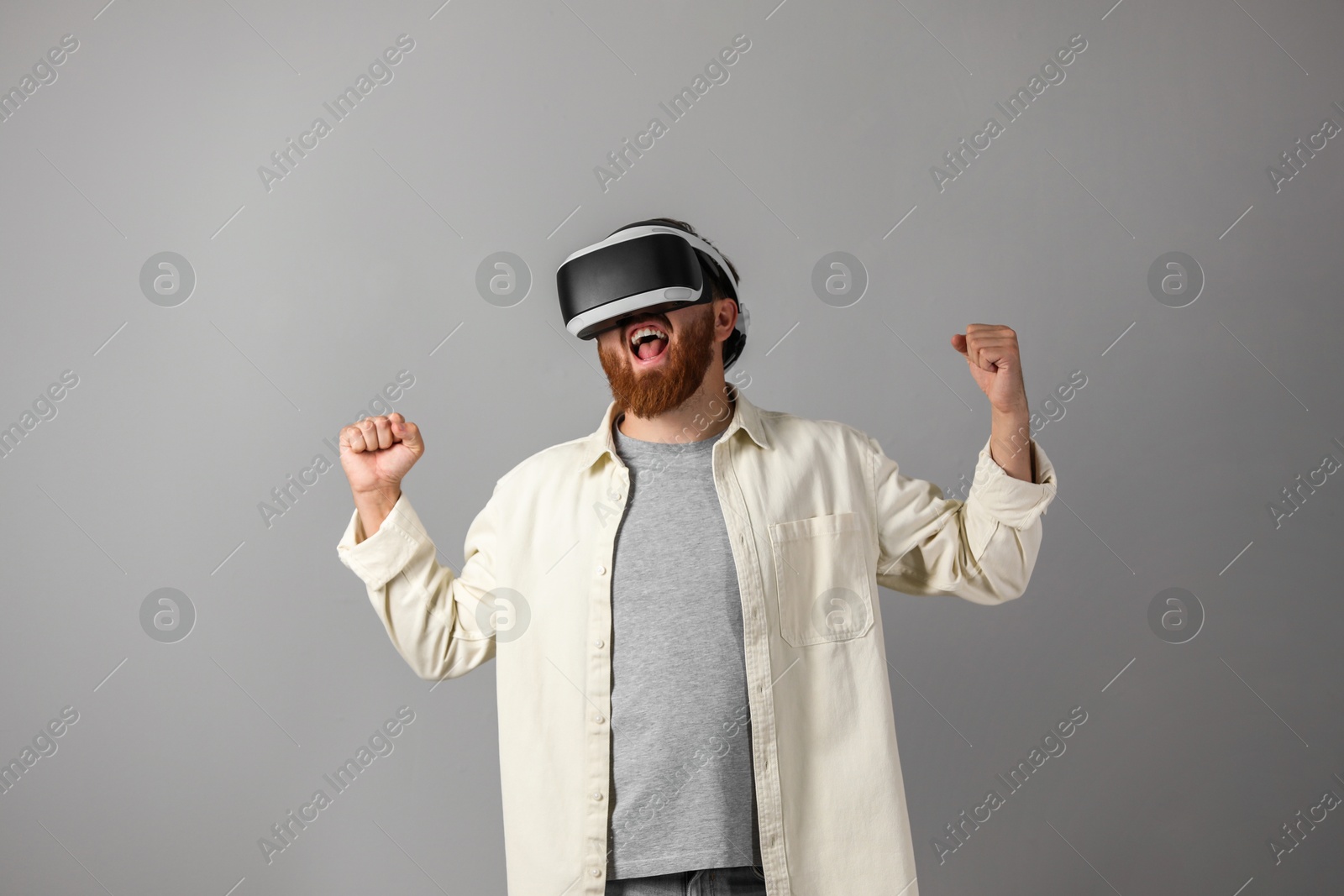 Photo of Emotional man using virtual reality headset on grey background