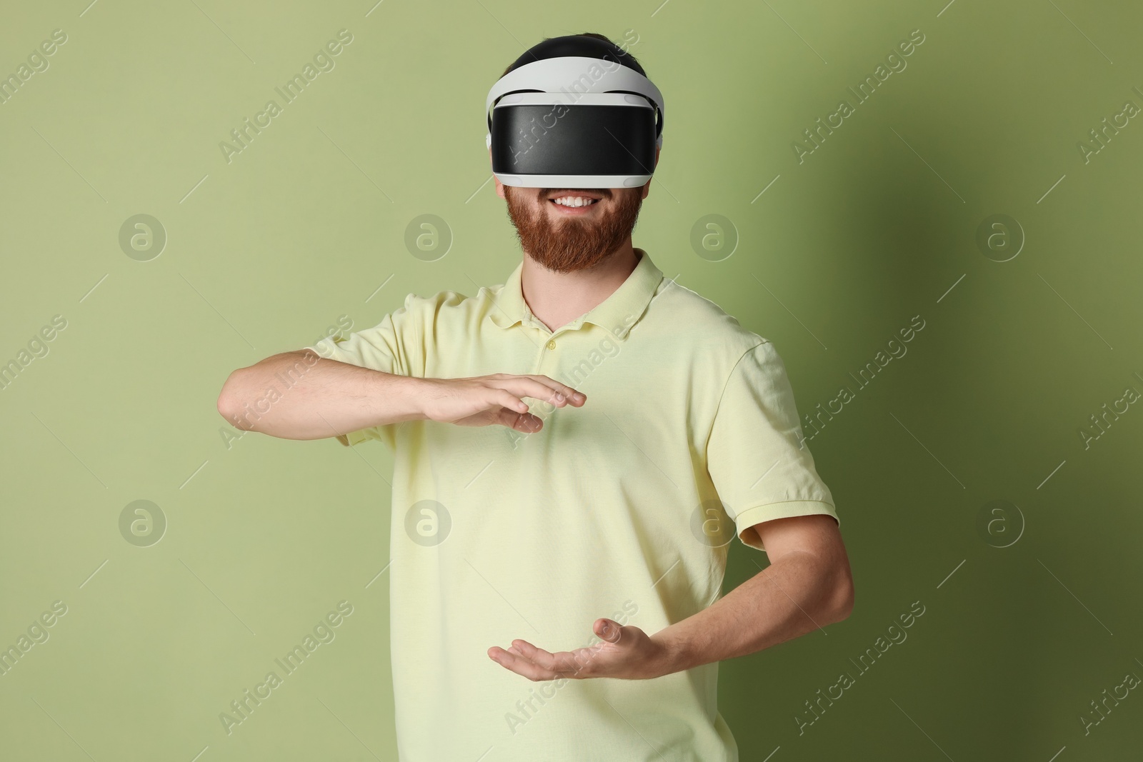 Photo of Smiling man using virtual reality headset on pale green background