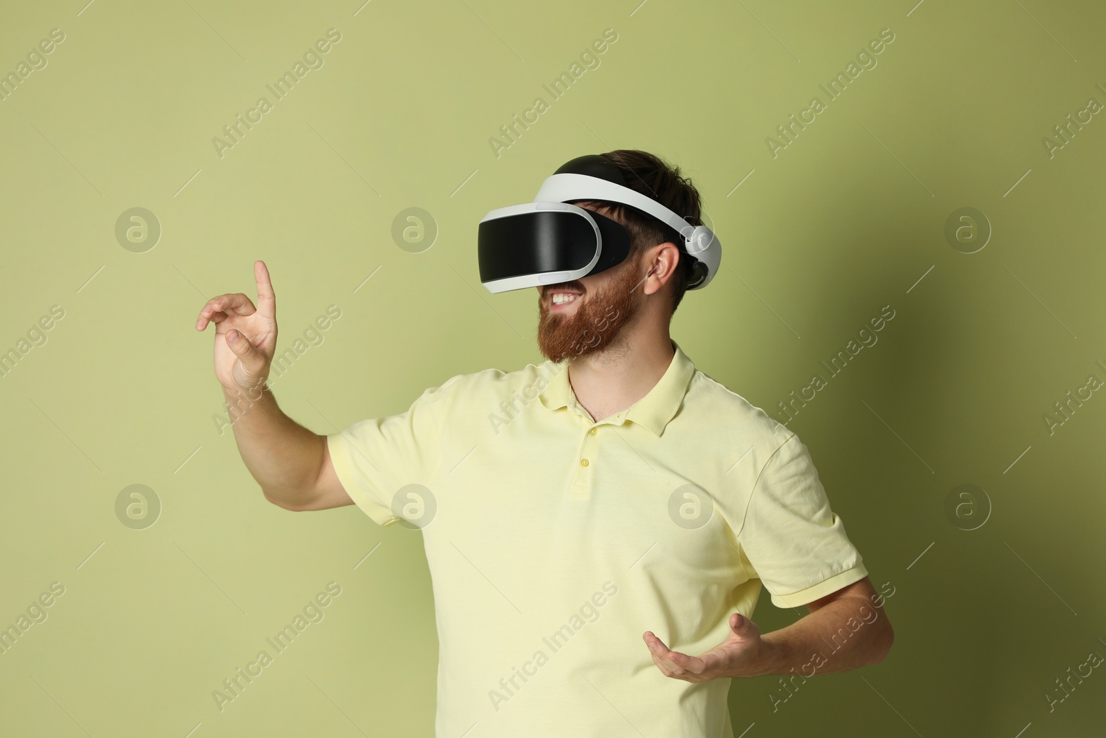 Photo of Smiling man using virtual reality headset on pale green background