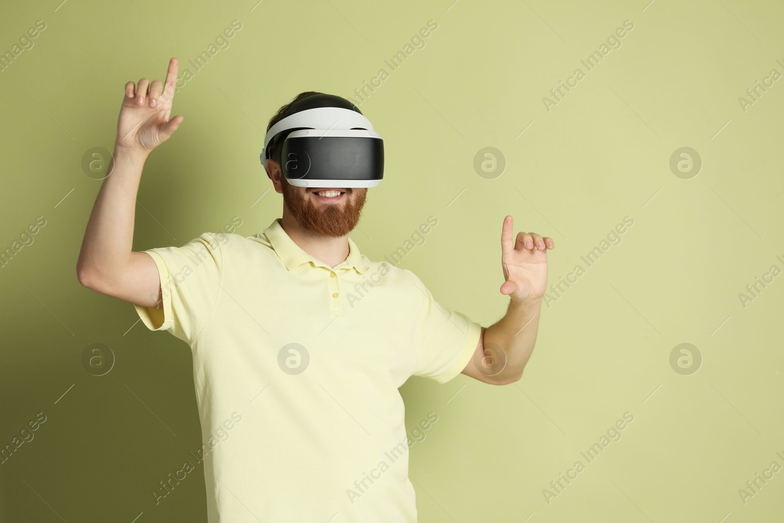 Photo of Smiling man using virtual reality headset on pale green background