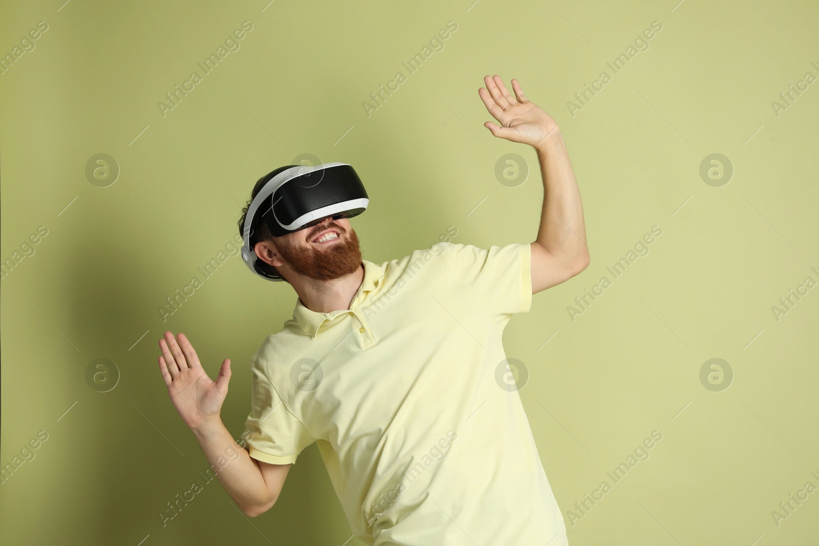 Photo of Smiling man using virtual reality headset on pale green background