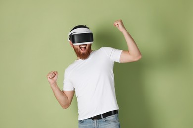 Photo of Emotional man using virtual reality headset on pale green background