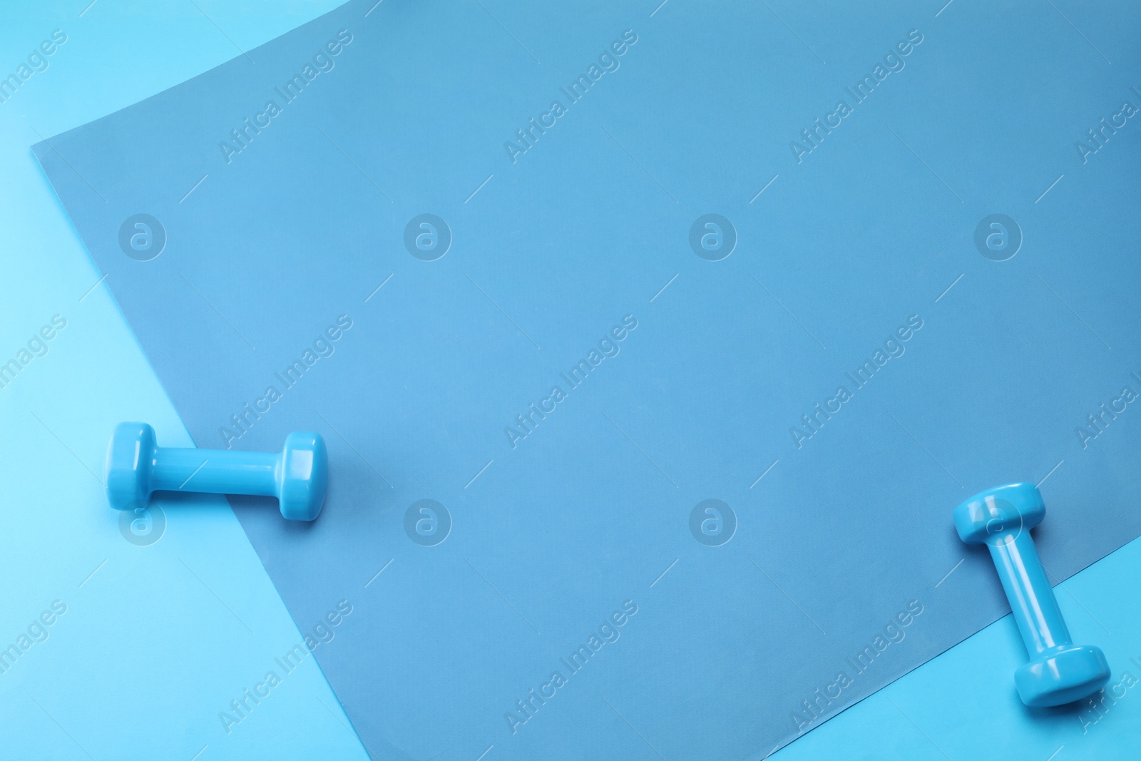 Photo of Two dumbbells on blue background, top view. Space for text