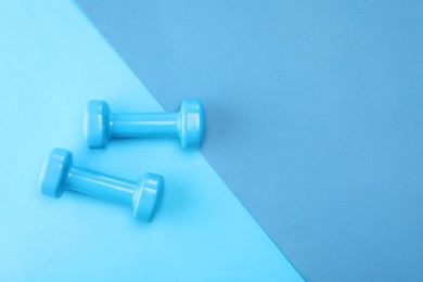 Photo of Two dumbbells on blue background, top view. Space for text