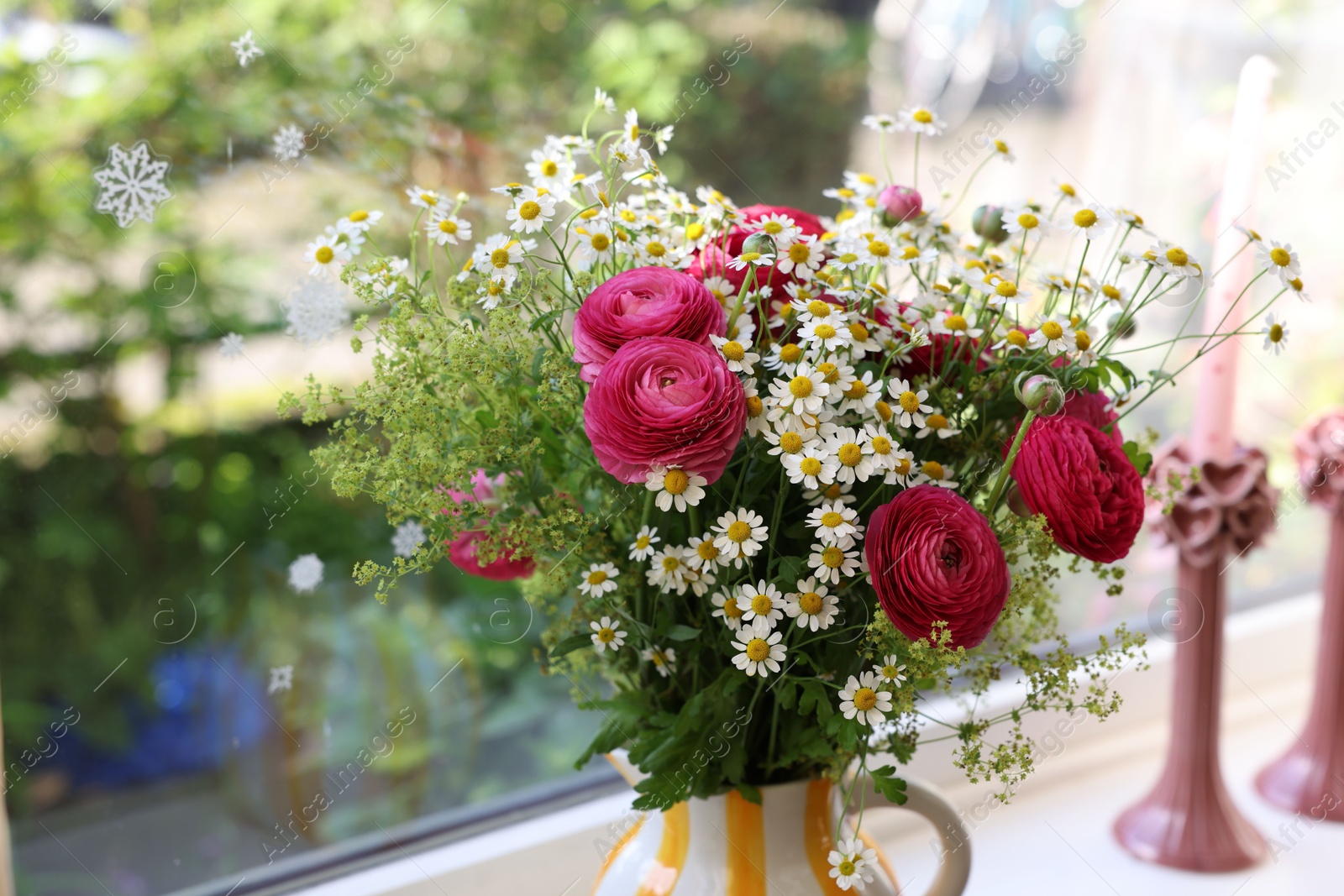 Photo of Beautiful ranunculus flowers and chamomiles in vase on windowsill indoors