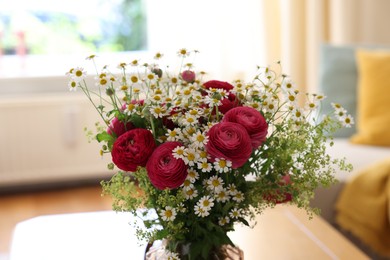 Photo of Beautiful ranunculus flowers and chamomiles in vase on table indoors