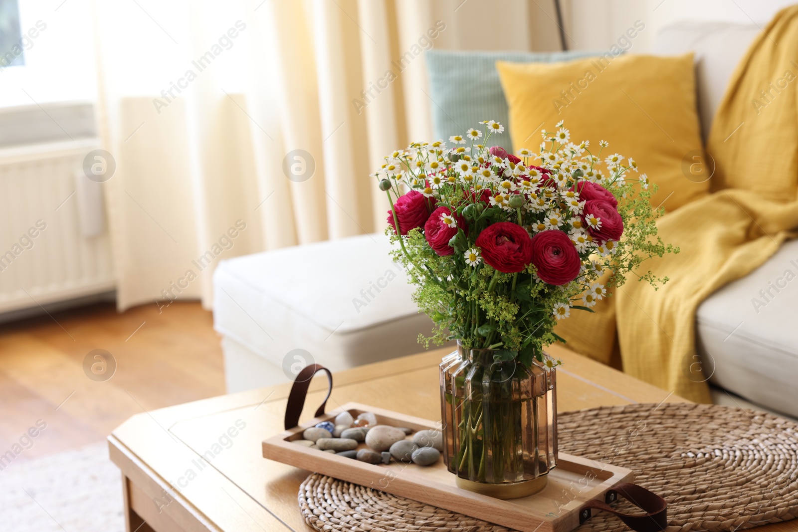 Photo of Beautiful ranunculus flowers and chamomiles in vase on table indoors