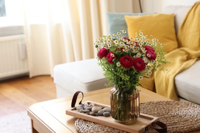 Photo of Beautiful ranunculus flowers and chamomiles in vase on table indoors