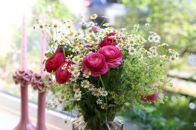 Beautiful ranunculus flowers and chamomiles near window indoors