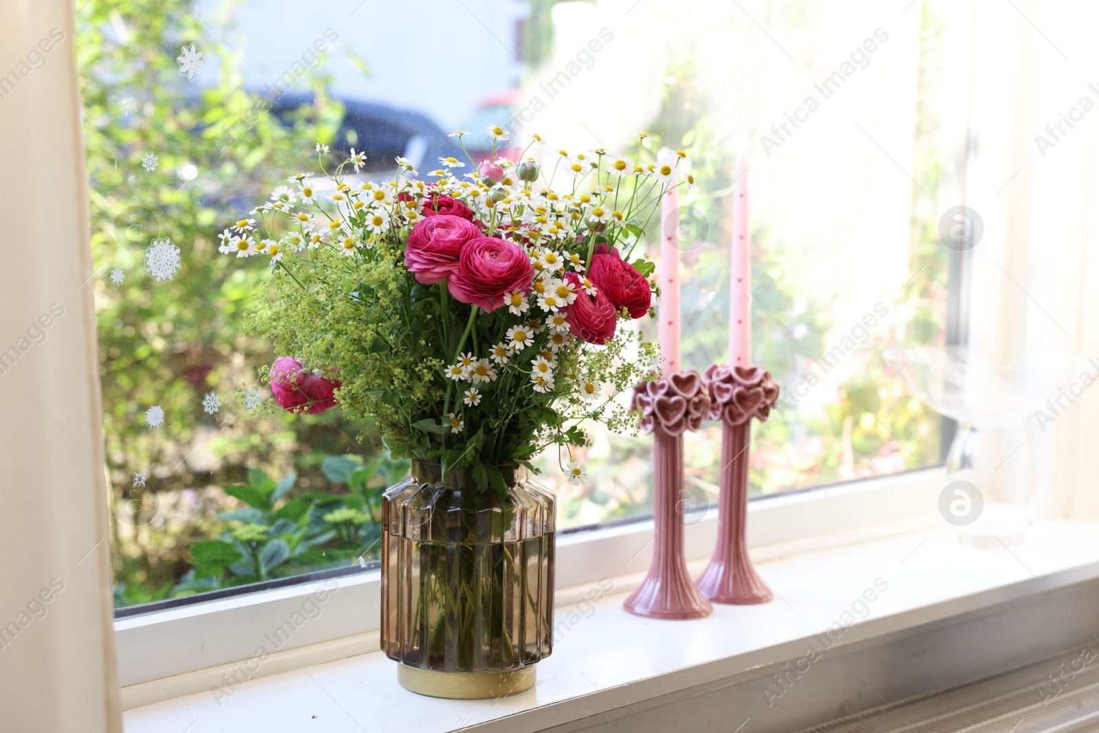 Photo of Beautiful ranunculus flowers and chamomiles in vase on windowsill indoors