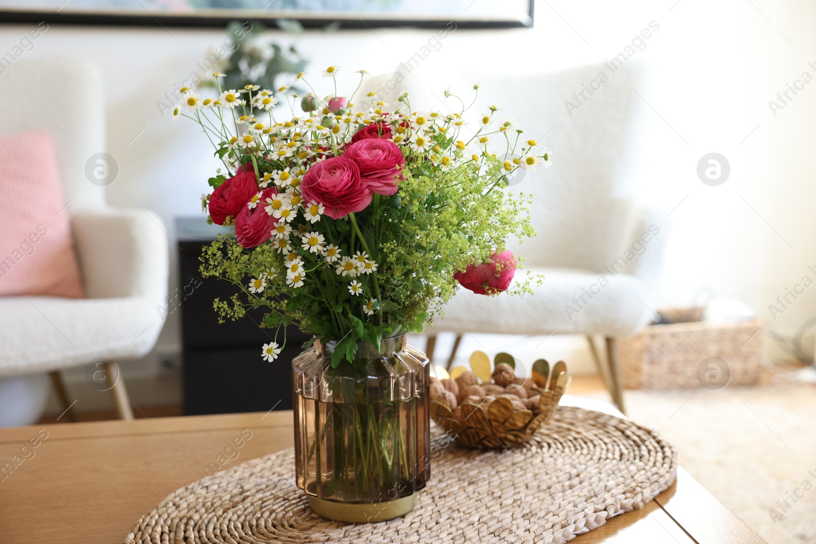 Photo of Beautiful ranunculus flowers and chamomiles in vase on table indoors