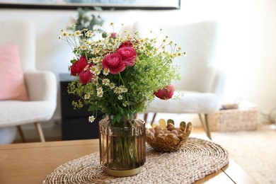 Photo of Beautiful ranunculus flowers and chamomiles in vase on table indoors