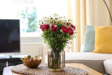 Beautiful ranunculus flowers and chamomiles in vase on table indoors