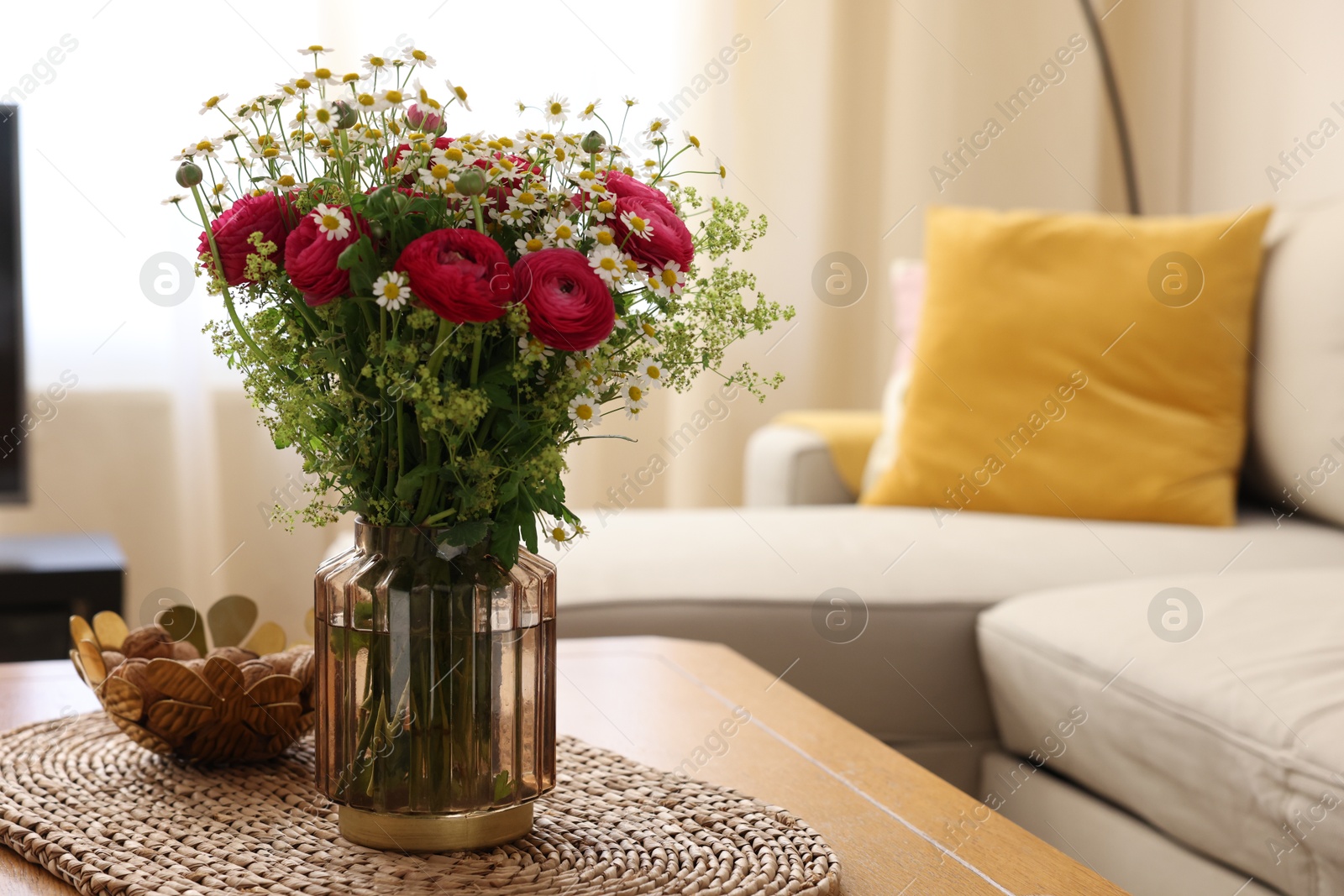 Photo of Beautiful ranunculus flowers and chamomiles in vase on table indoors