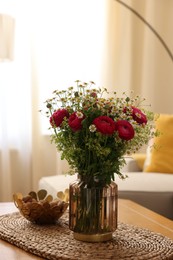 Photo of Beautiful ranunculus flowers and chamomiles in vase on table indoors