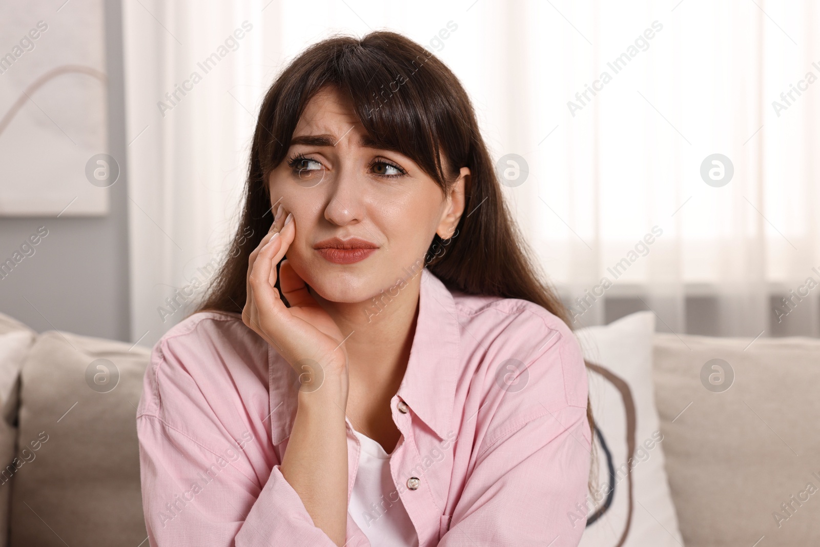 Photo of Upset young woman suffering from toothache indoors