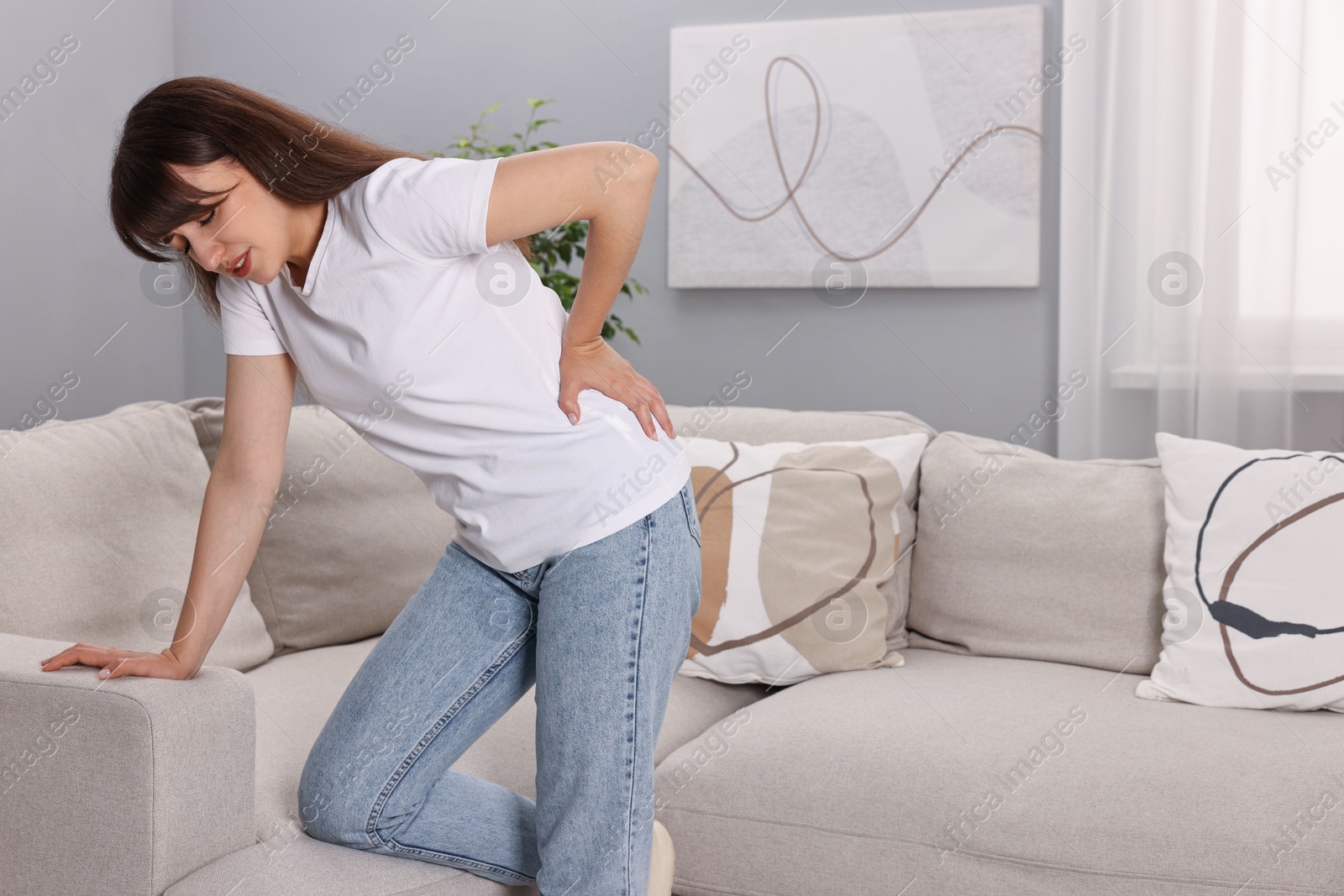 Photo of Upset woman suffering from back pain at home