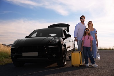Photo of Happy family with suitcase near car outdoors
