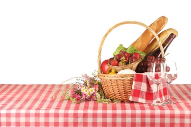 Photo of Picnic wicker basket with checkered napkin, food and bottle of wine on table against white background. Space for text