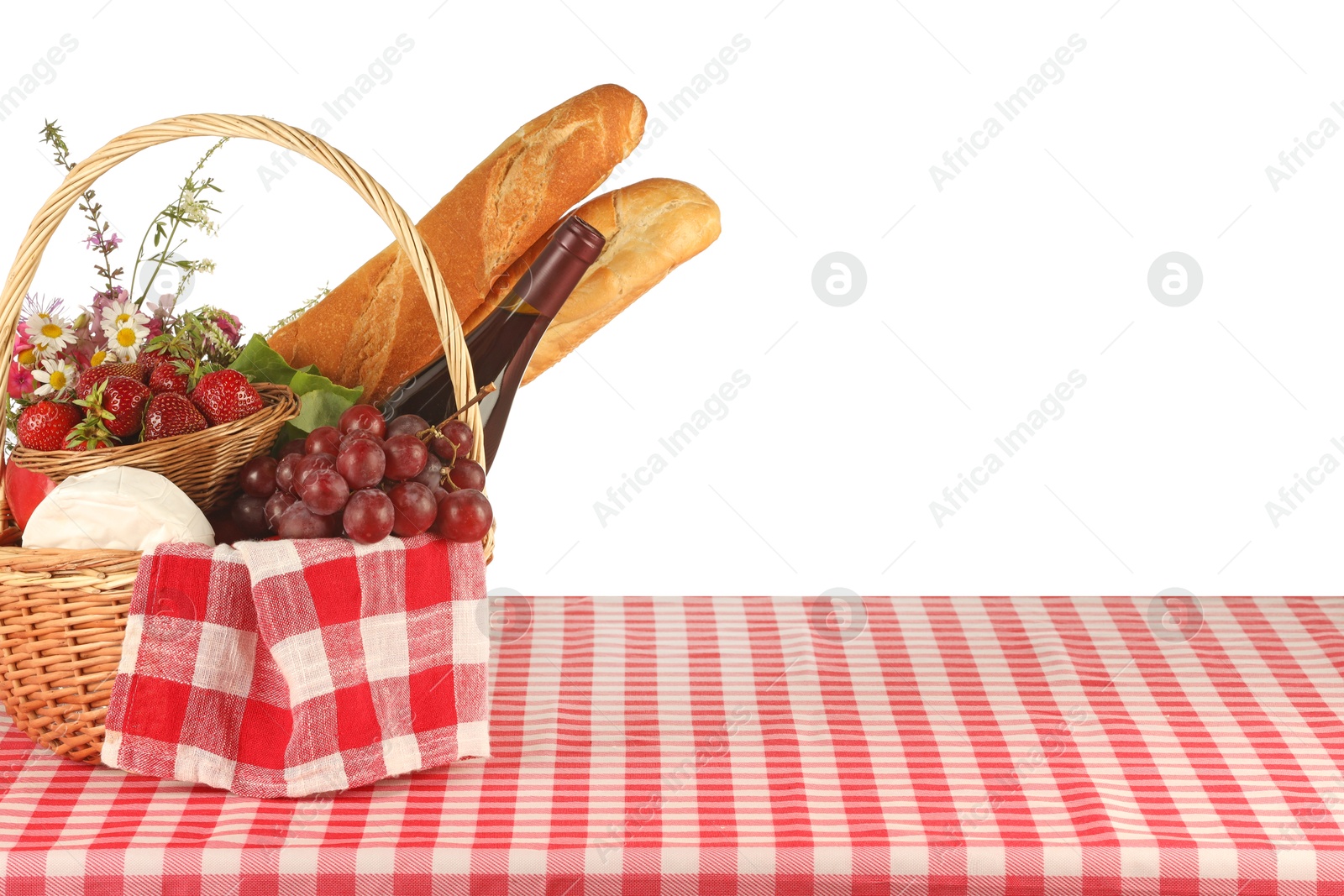 Photo of Picnic wicker basket with checkered napkin, food and bottle of wine on table against white background. Space for text